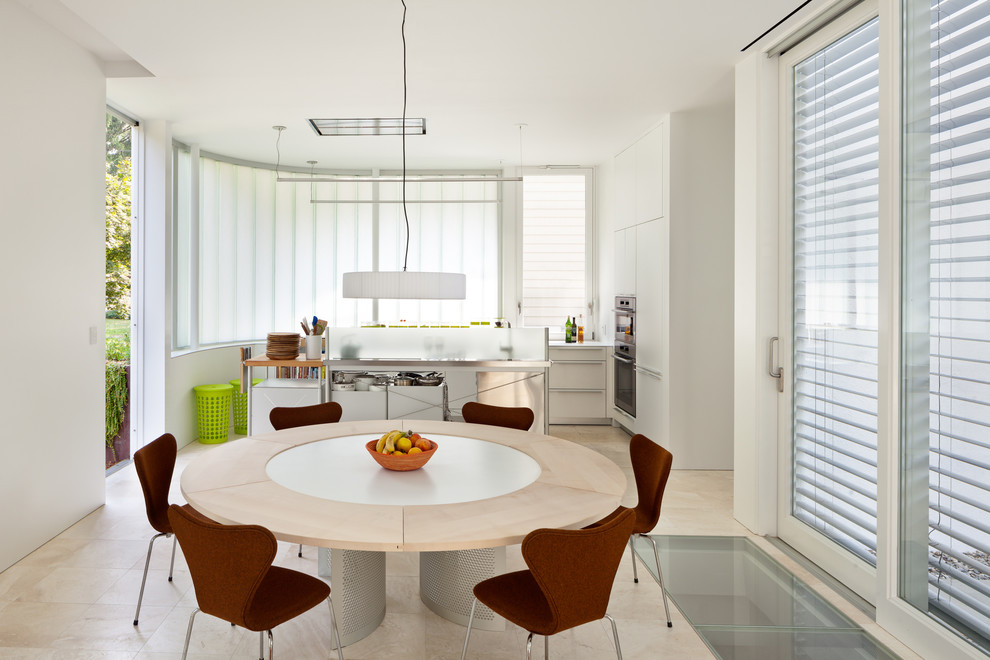 Réalisation d'une salle à manger ouverte sur la cuisine design de taille moyenne avec un mur blanc et un sol en travertin.
