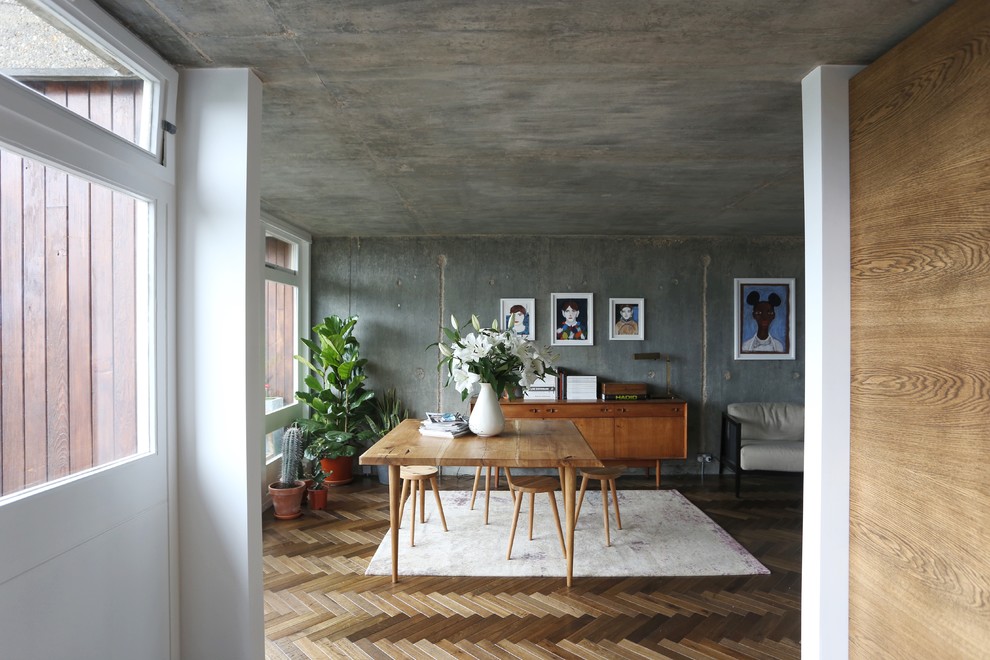 Urban dining room in London with grey walls, medium hardwood flooring and no fireplace.