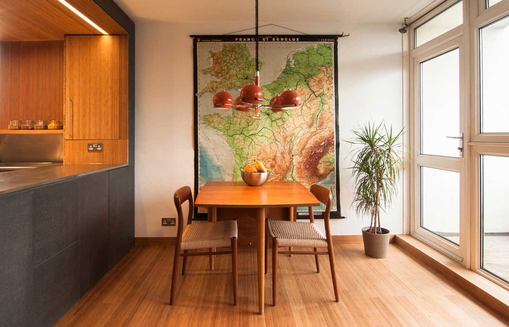 Cette photo montre une petite salle à manger ouverte sur la cuisine tendance avec un mur blanc et parquet en bambou.