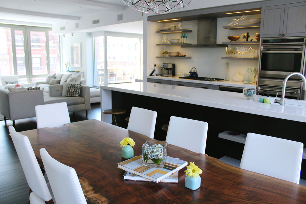 Foto di una sala da pranzo aperta verso la cucina moderna di medie dimensioni con pareti bianche, parquet scuro e pavimento nero