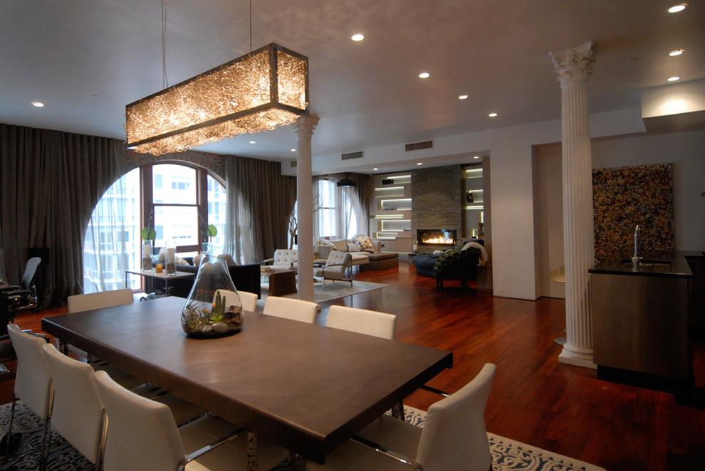 Cette image montre une petite salle à manger ouverte sur le salon design avec un sol en bois brun et un manteau de cheminée en pierre.
