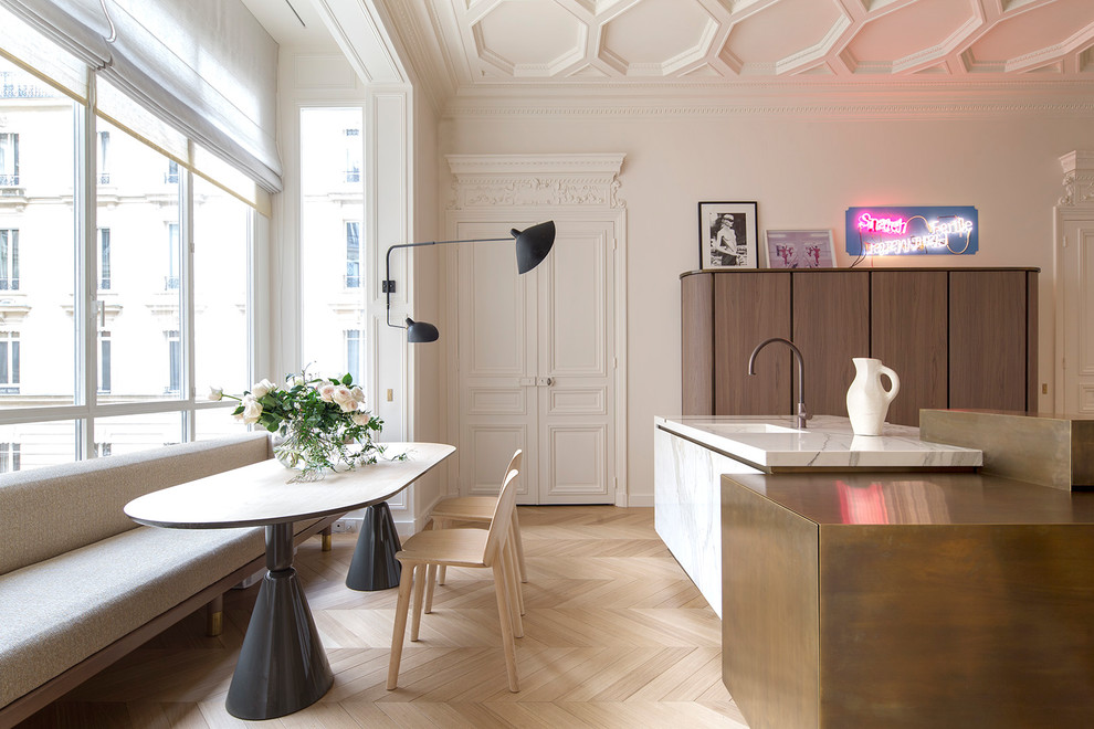 Cette photo montre une salle à manger ouverte sur la cuisine chic avec un mur blanc, parquet clair, un sol beige et éclairage.