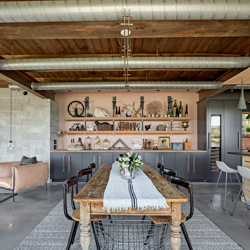 Urban concrete floor, gray floor and exposed beam dining room photo in New York with pink walls