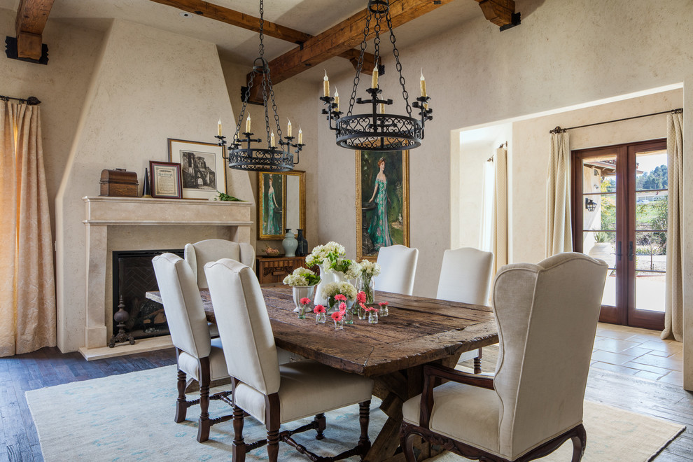 Photo of a mediterranean dining room in Los Angeles with beige walls, dark hardwood flooring and a standard fireplace.