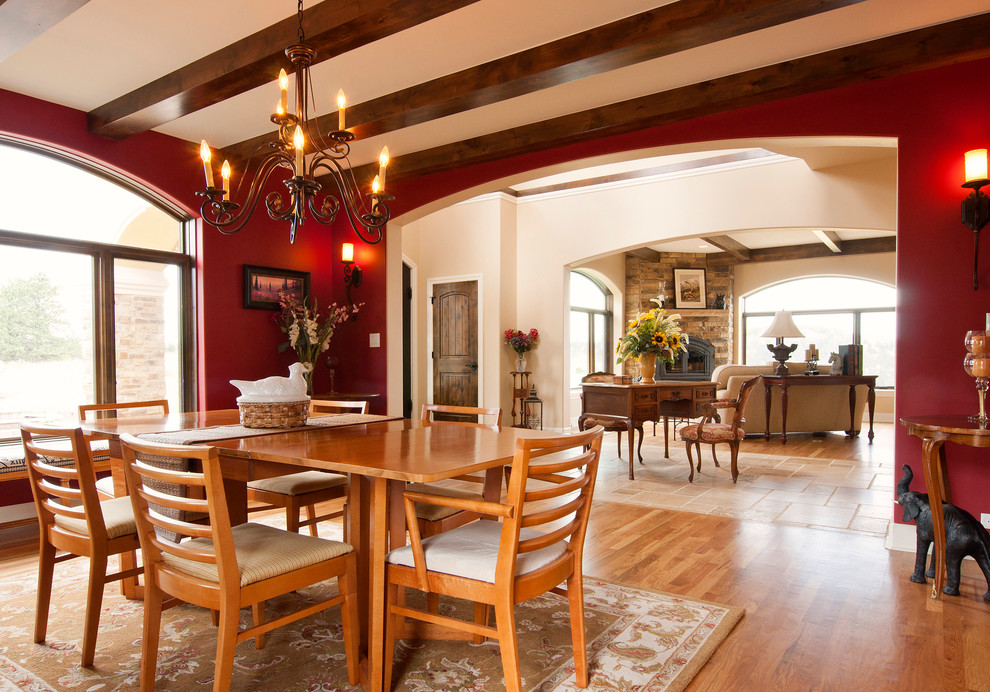 Aménagement d'une salle à manger ouverte sur le salon méditerranéenne avec un mur rouge, parquet clair, une cheminée d'angle et éclairage.