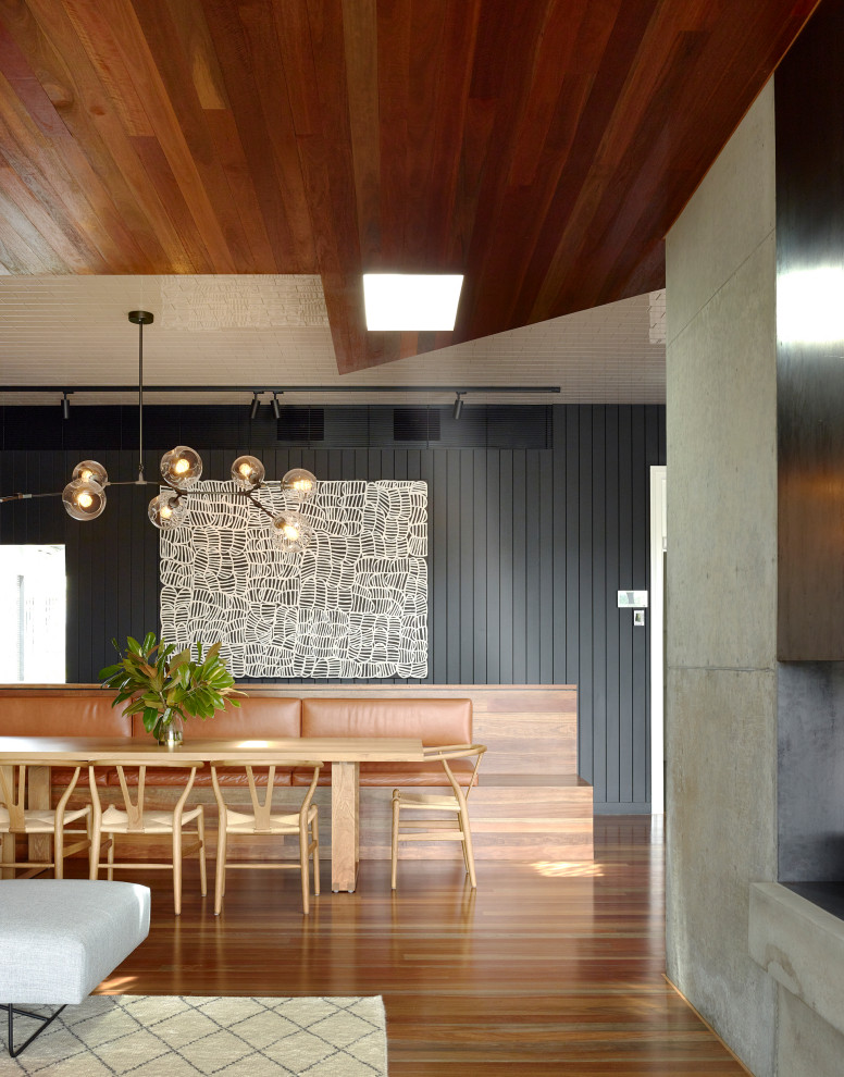Immagine di una sala da pranzo aperta verso il soggiorno minimal con pareti nere, pavimento in legno massello medio, pavimento marrone, soffitto in legno e pareti in perlinato