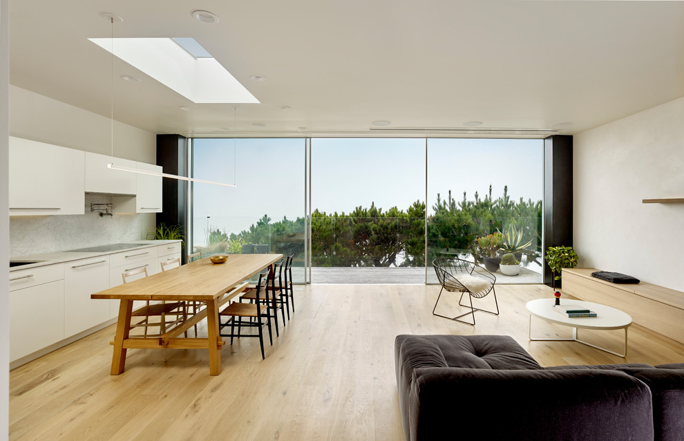 Esempio di una sala da pranzo aperta verso la cucina design di medie dimensioni con pareti bianche, pavimento in laminato e pavimento marrone