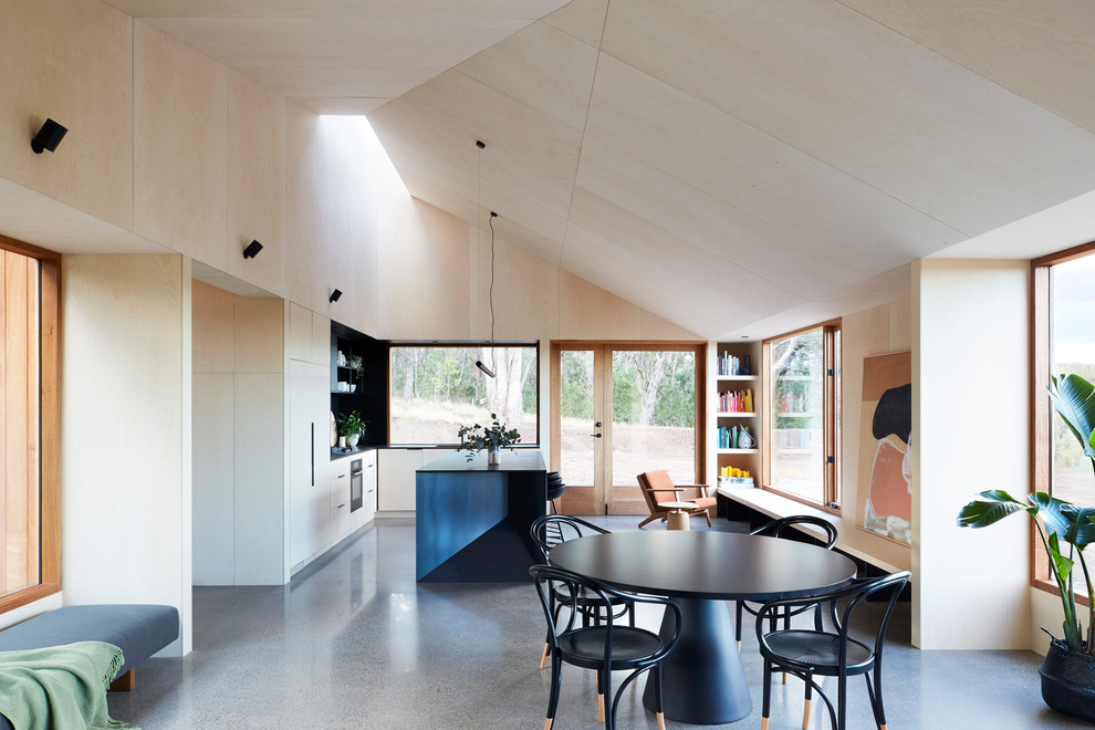 Foto di una sala da pranzo aperta verso la cucina design con pareti beige, pavimento in cemento e pavimento grigio