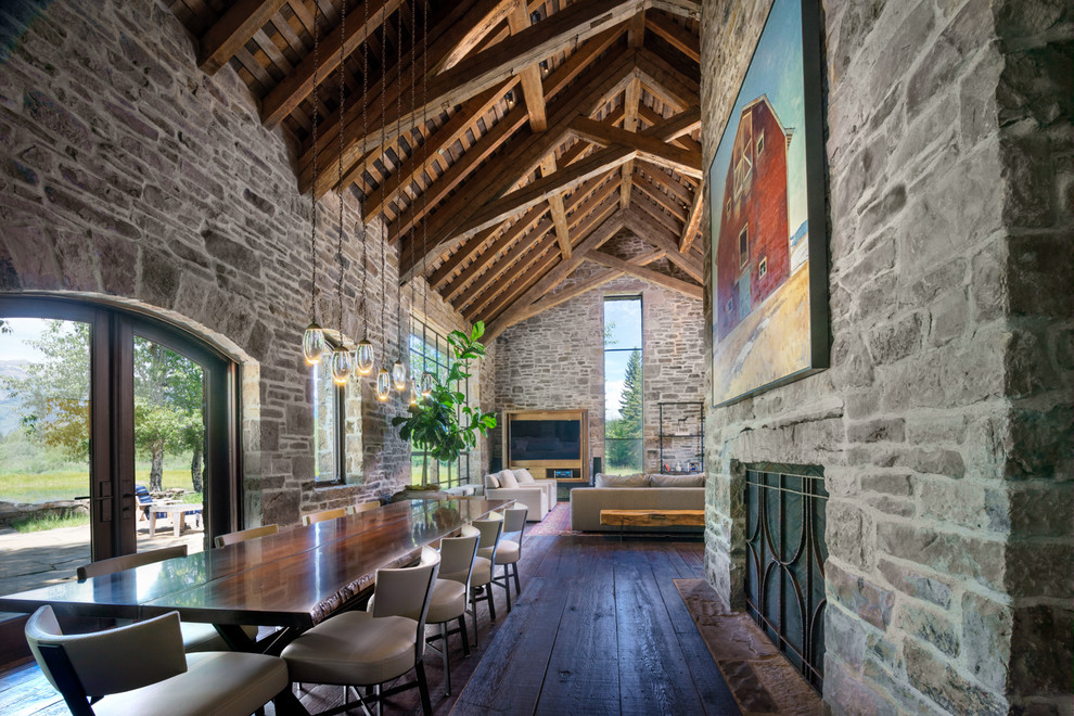 Immagine di una grande sala da pranzo aperta verso il soggiorno design con pareti beige, parquet scuro, camino classico e cornice del camino in pietra