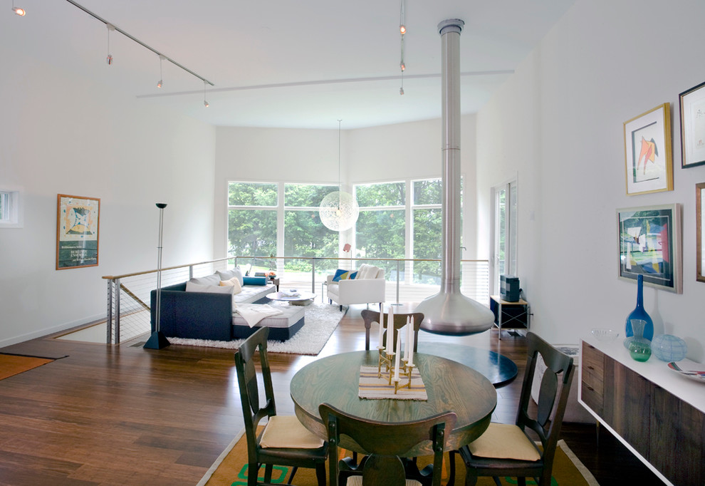 Idée de décoration pour une salle à manger minimaliste avec parquet foncé et cheminée suspendue.