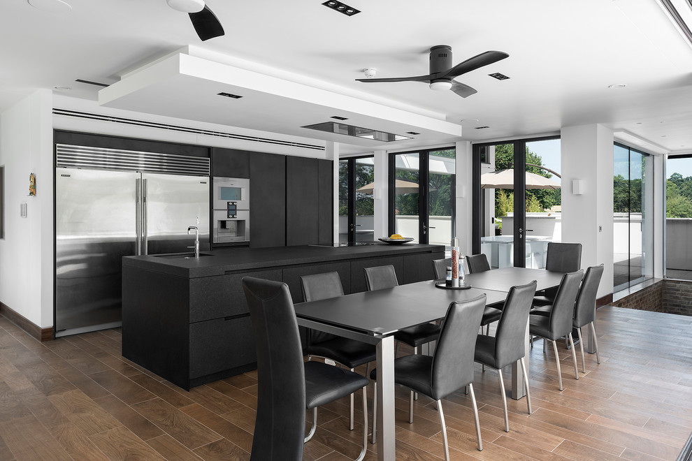 Large contemporary open plan dining room in Hampshire with dark hardwood flooring, white walls and no fireplace.