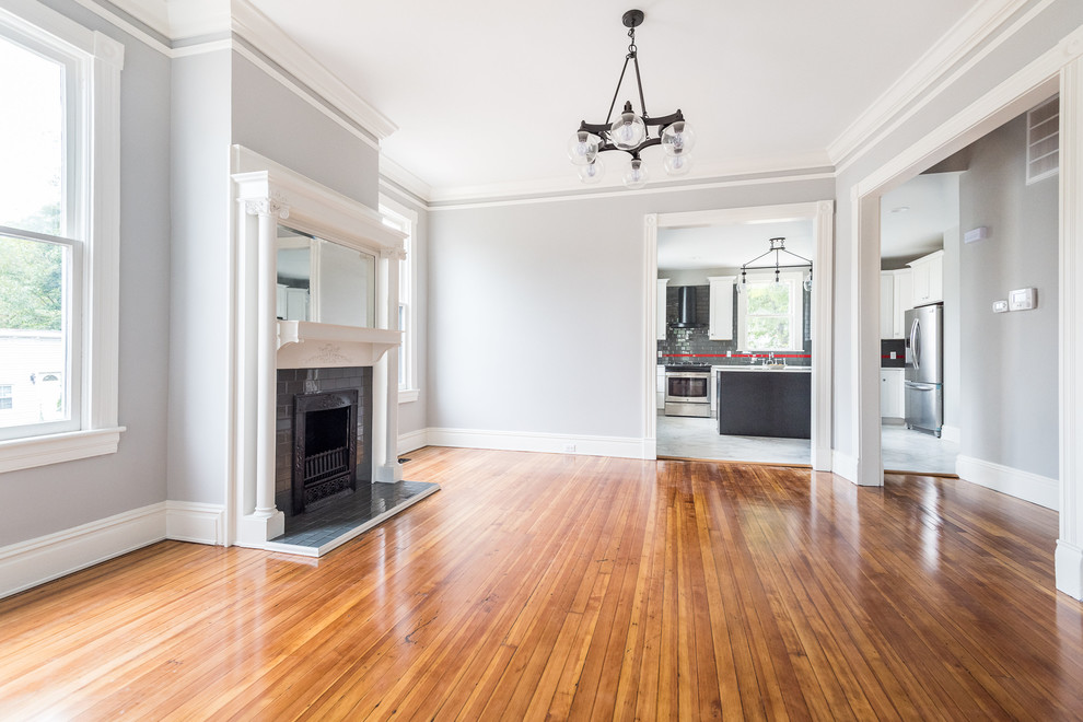 Example of a large trendy light wood floor dining room design in Wilmington with gray walls, a standard fireplace and a brick fireplace
