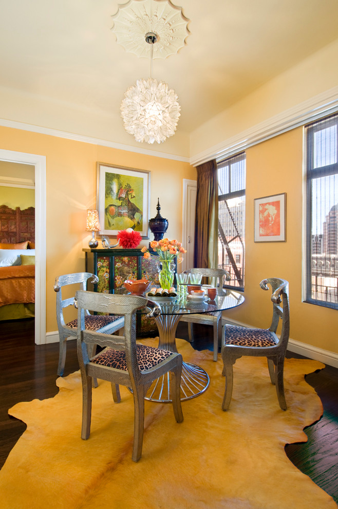 Exemple d'une salle à manger éclectique avec parquet foncé et un mur jaune.
