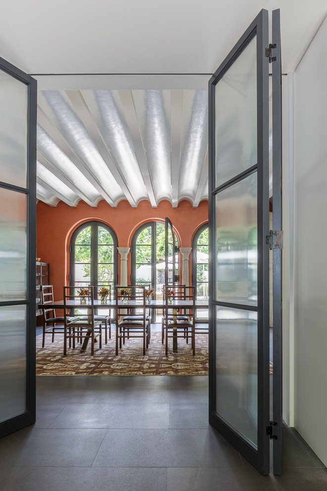 Réalisation d'une grande salle à manger méditerranéenne fermée avec un mur orange, sol en béton ciré et un sol gris.