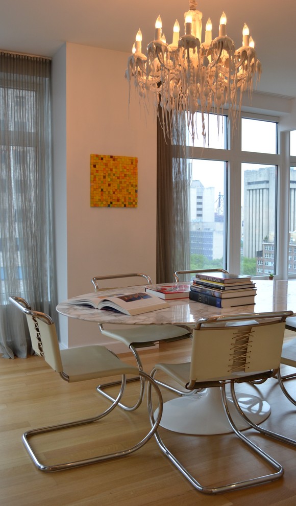 This is an example of a contemporary dining room in New York with white walls.