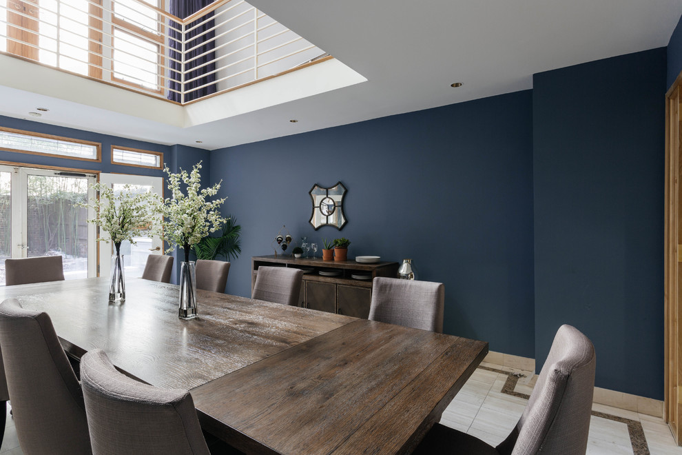 Foto di una grande sala da pranzo aperta verso la cucina classica con pareti blu, pavimento in pietra calcarea e nessun camino