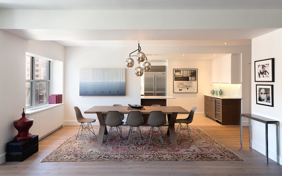 Cette image montre une salle à manger ouverte sur la cuisine design de taille moyenne avec un mur blanc, parquet clair et un sol marron.