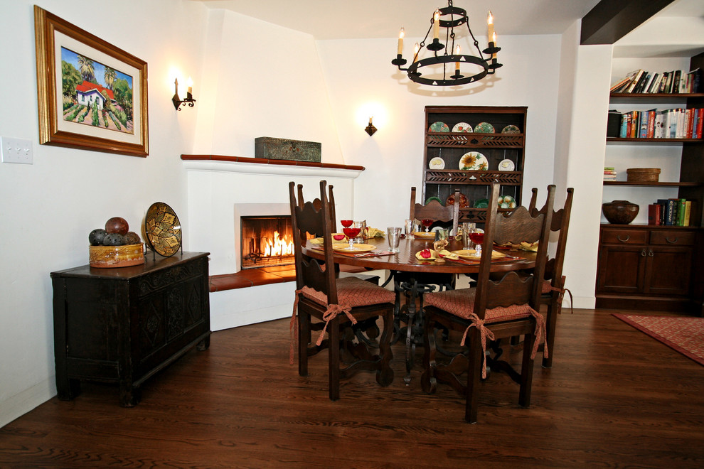 Inspiration pour une salle à manger méditerranéenne avec un mur blanc, un sol en bois brun, une cheminée d'angle et un manteau de cheminée en plâtre.