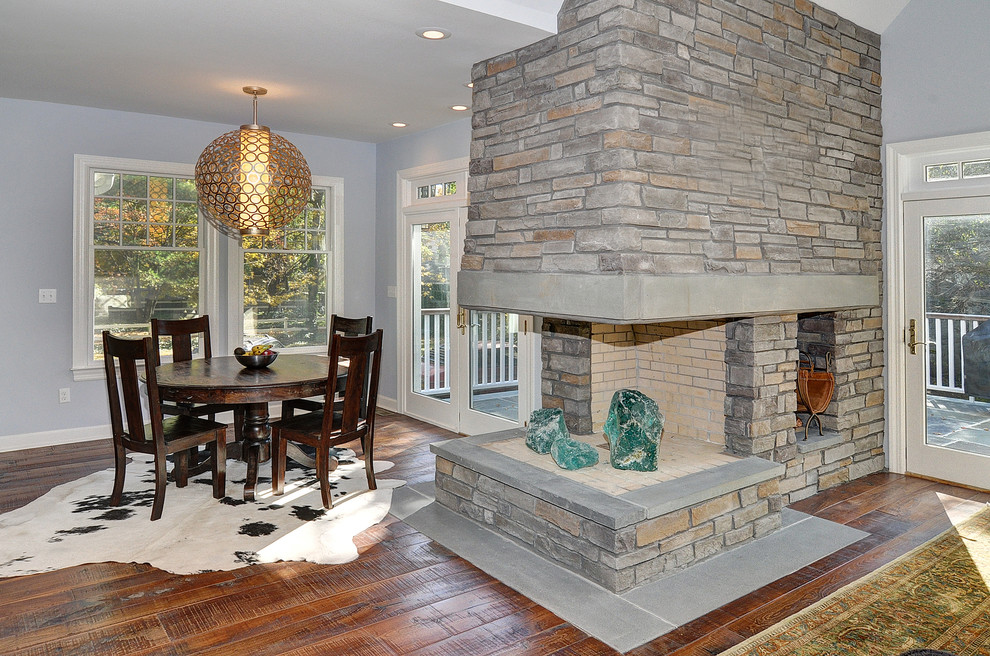 Пример оригинального дизайна: столовая в стиле фьюжн с серыми стенами, паркетным полом среднего тона, двусторонним камином и фасадом камина из камня