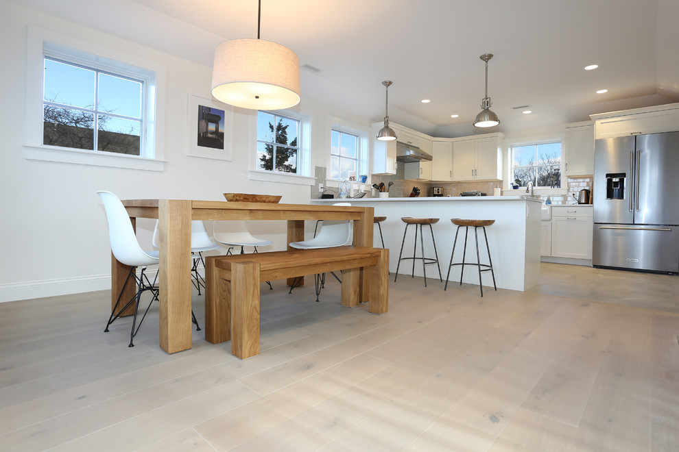 Réalisation d'une petite salle à manger ouverte sur la cuisine minimaliste avec un mur blanc, parquet clair et un sol gris.