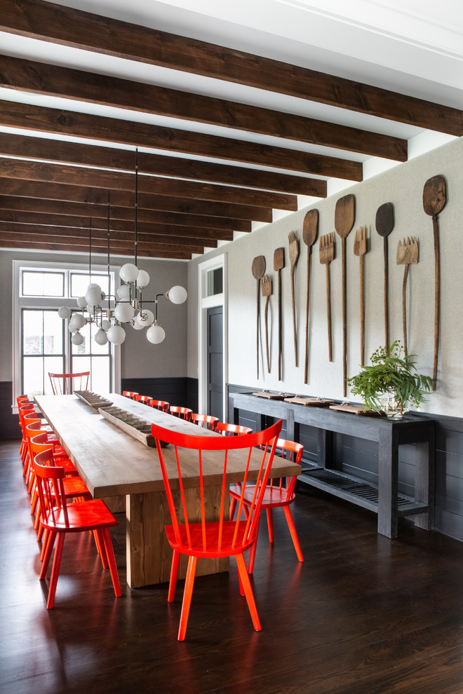 Immagine di una grande sala da pranzo aperta verso la cucina country con pareti nere, parquet scuro e pavimento marrone