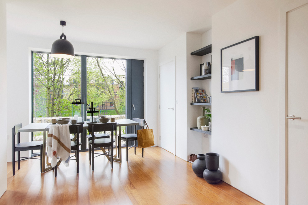 Inspiration pour une salle à manger minimaliste avec un mur blanc, un sol en bois brun et un sol marron.