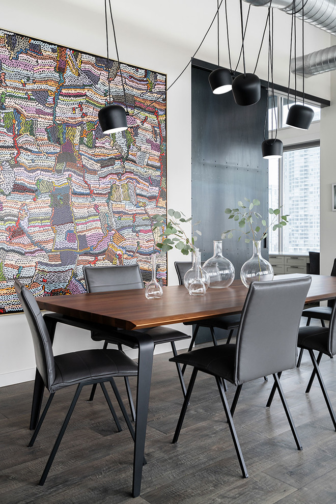 Cette photo montre une salle à manger ouverte sur le salon industrielle de taille moyenne avec un mur gris, un sol en bois brun et un sol gris.