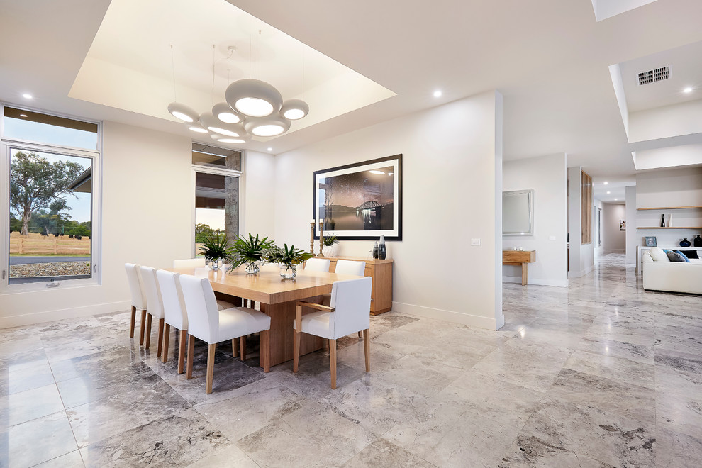 Immagine di una grande sala da pranzo aperta verso la cucina minimalista con pareti grigie e pavimento in pietra calcarea