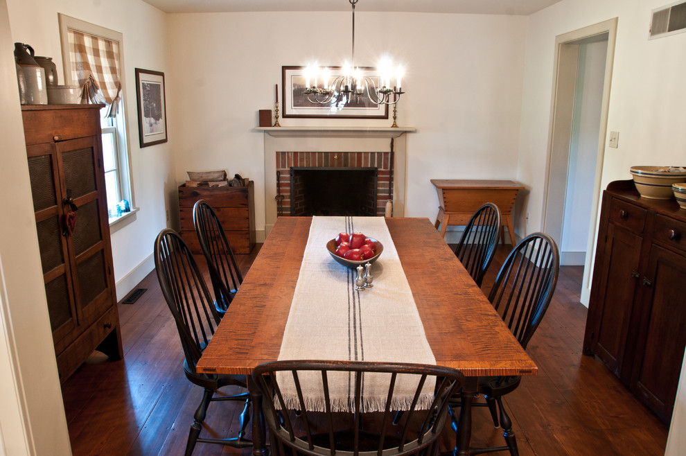 Idée de décoration pour une salle à manger tradition avec un mur blanc, un sol en bois brun, une cheminée standard et un manteau de cheminée en brique.