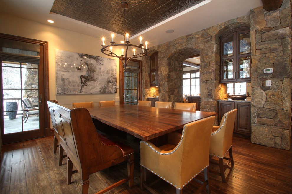 Réalisation d'une salle à manger ouverte sur la cuisine chalet avec un mur blanc et parquet foncé.