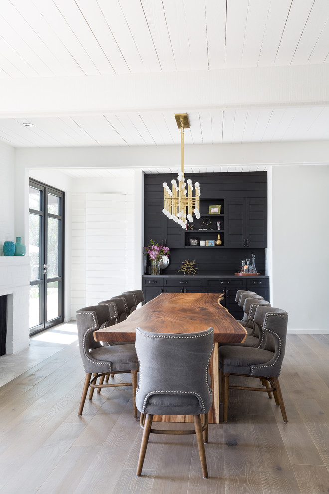 Ispirazione per una grande sala da pranzo aperta verso il soggiorno minimalista con pareti bianche, parquet chiaro, camino classico e cornice del camino in mattoni