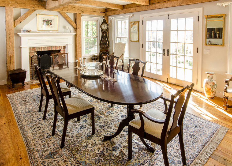 Idée de décoration pour une salle à manger ouverte sur la cuisine champêtre de taille moyenne avec un mur beige, un sol en bois brun, une cheminée standard et un manteau de cheminée en brique.