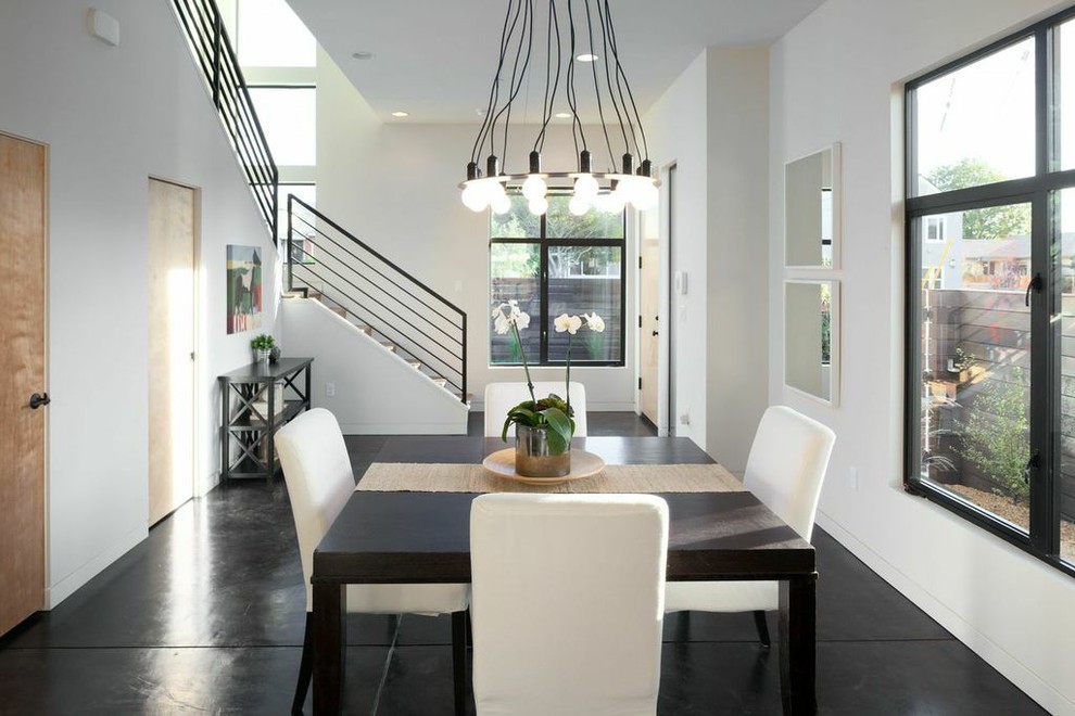 Aménagement d'une salle à manger contemporaine avec un mur blanc, sol en béton ciré et un sol noir.