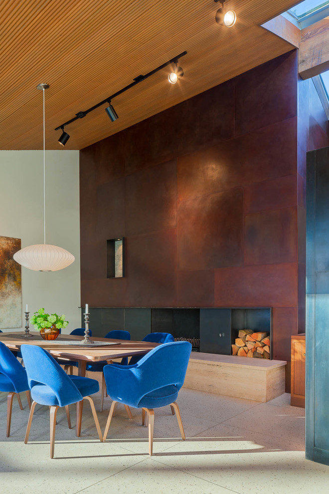 Photo of a contemporary dining room in Vancouver with grey walls, a standard fireplace and a metal fireplace surround.