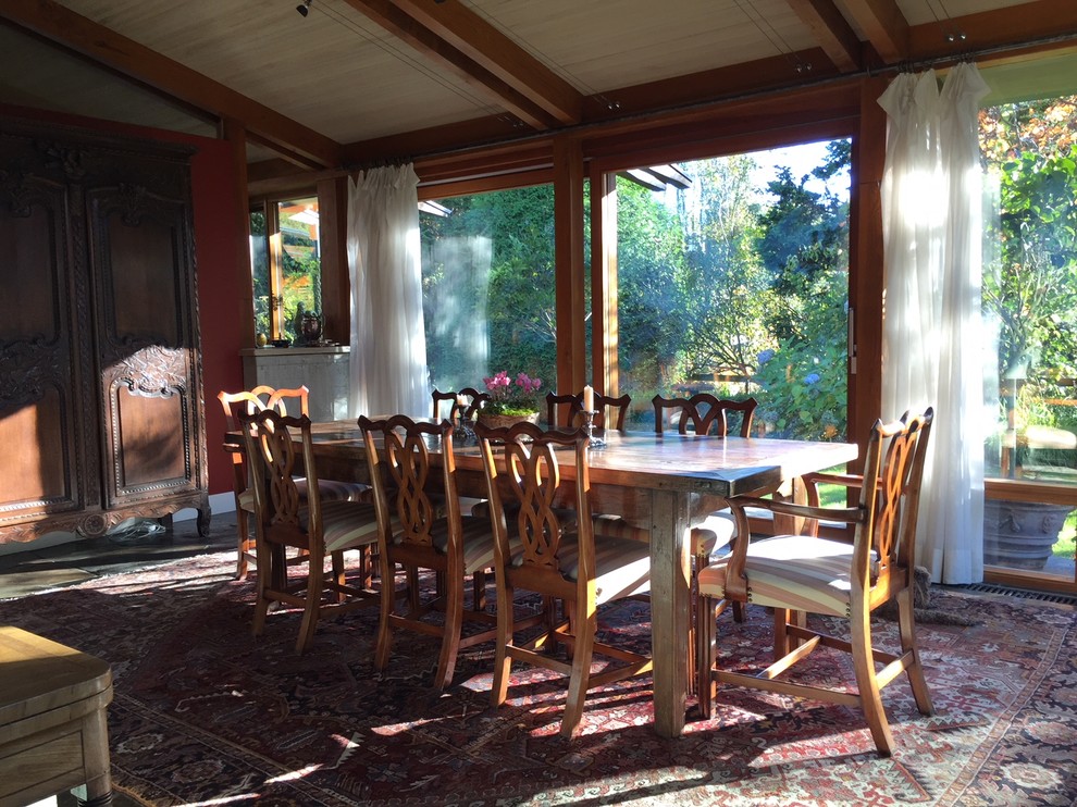 Immagine di una grande sala da pranzo aperta verso la cucina chic con pareti rosse, pavimento in ardesia, camino bifacciale, cornice del camino in cemento e pavimento grigio