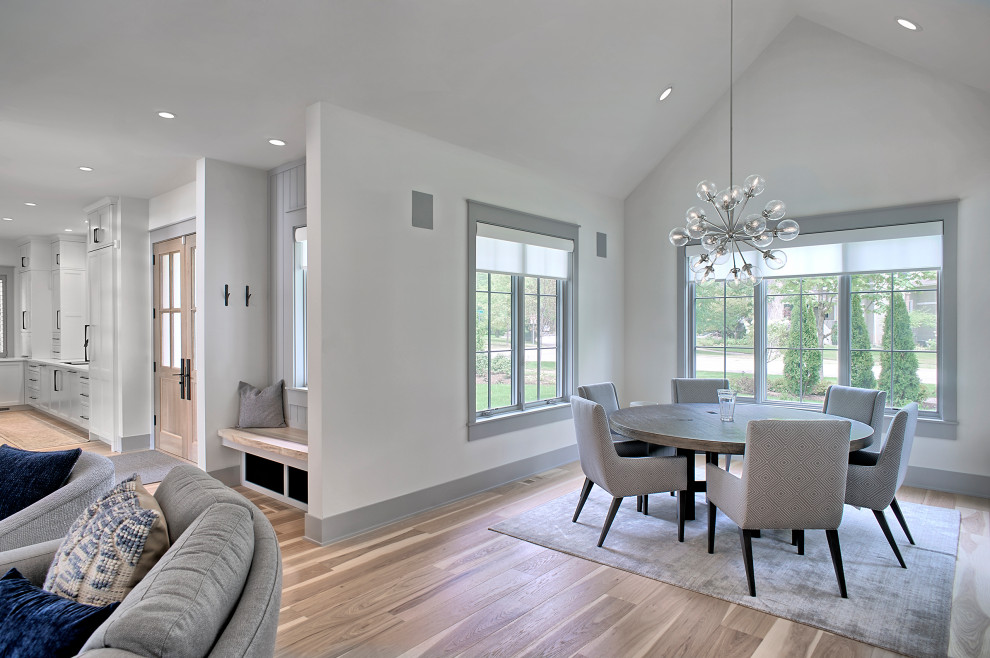 Immagine di una sala da pranzo aperta verso il soggiorno classica di medie dimensioni con pareti bianche, pavimento in legno massello medio, pavimento marrone e soffitto a volta