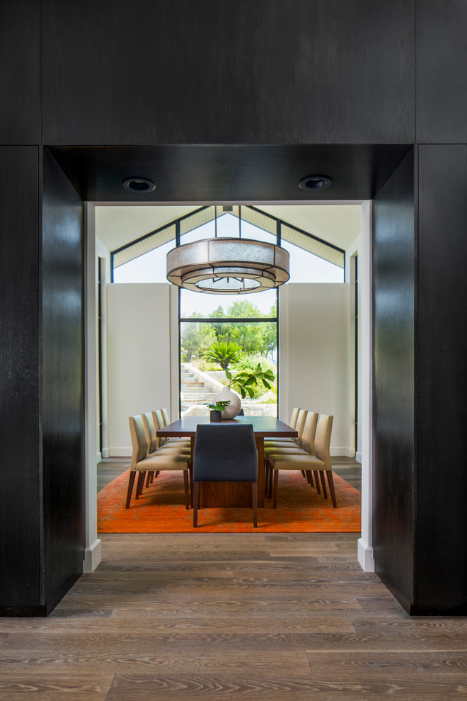 Cette image montre une salle à manger design fermée avec un mur blanc et un sol en bois brun.