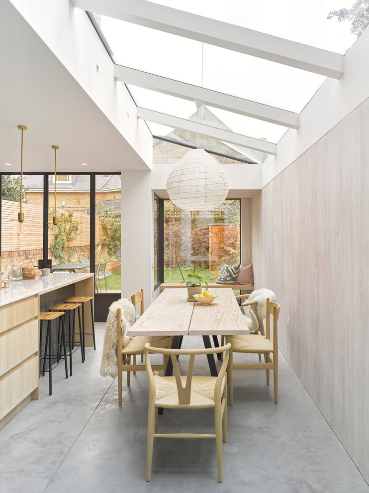 Aménagement d'une salle à manger ouverte sur la cuisine contemporaine avec un mur beige, sol en béton ciré et un sol gris.