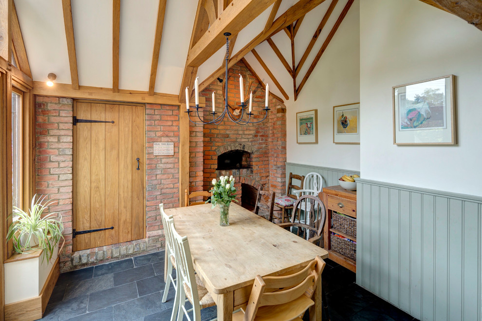 Design ideas for a medium sized country kitchen/dining room in Kent with green walls, slate flooring, a standard fireplace, a brick fireplace surround and grey floors.