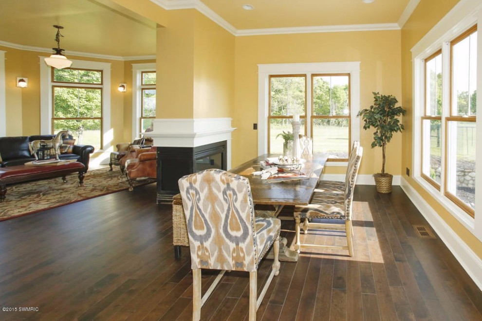 Example of a mid-sized ornate medium tone wood floor kitchen/dining room combo design in Grand Rapids with yellow walls and a two-sided fireplace