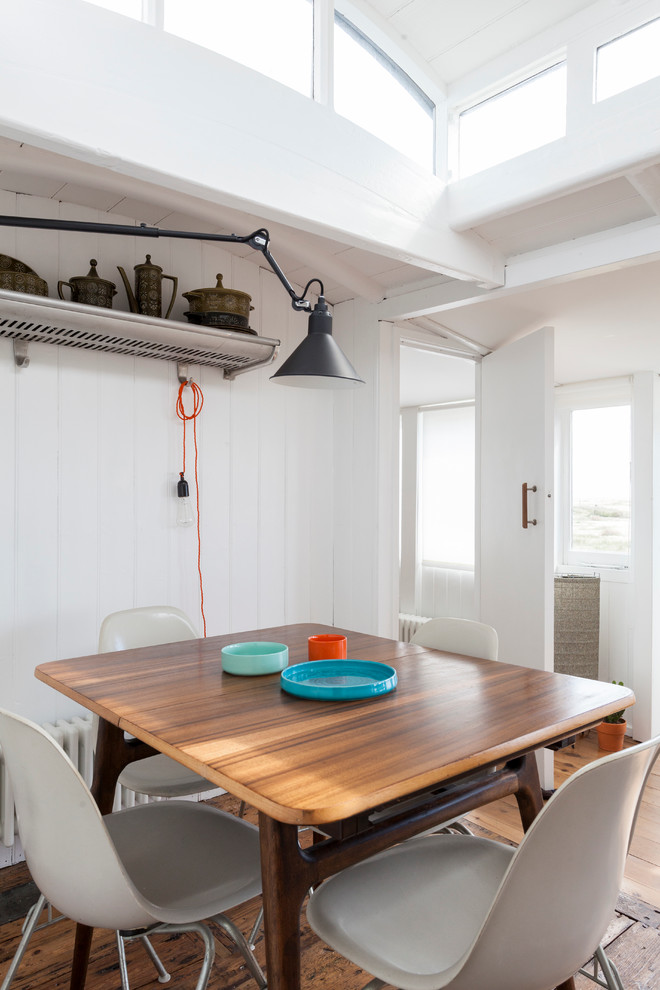 Example of a danish medium tone wood floor kitchen/dining room combo design in London with white walls