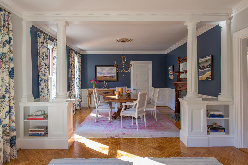 Cette image montre une grande salle à manger victorienne avec un mur bleu, un sol en bois brun, une cheminée standard et un manteau de cheminée en carrelage.