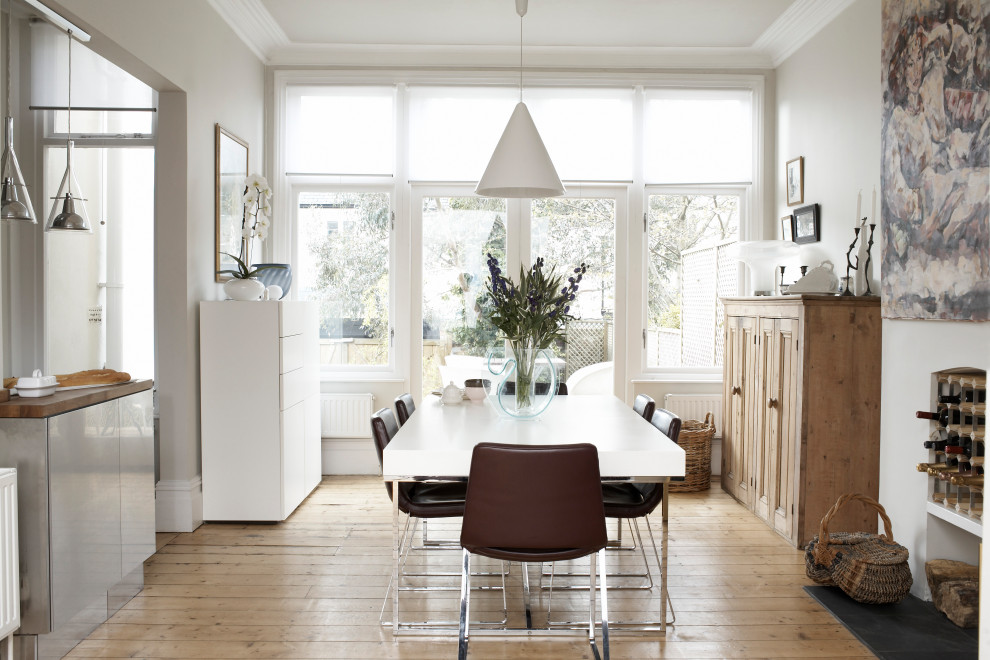 This is an example of a small contemporary dining room in Cardiff with white walls, light hardwood flooring and beige floors.