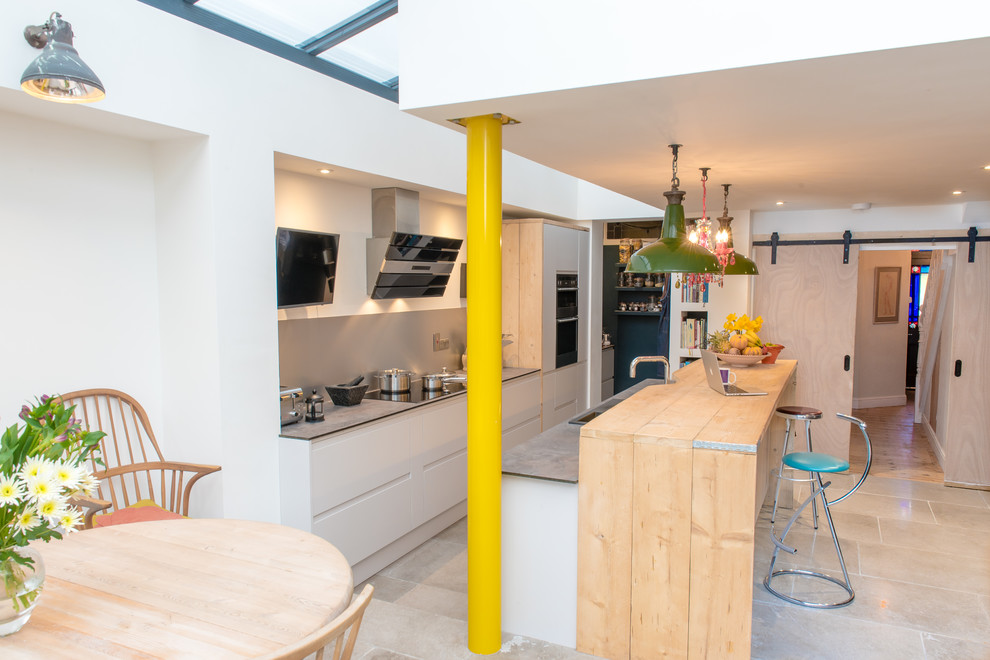 Mittelgroße Moderne Wohnküche ohne Kamin mit weißer Wandfarbe, Kalkstein und beigem Boden in Devon