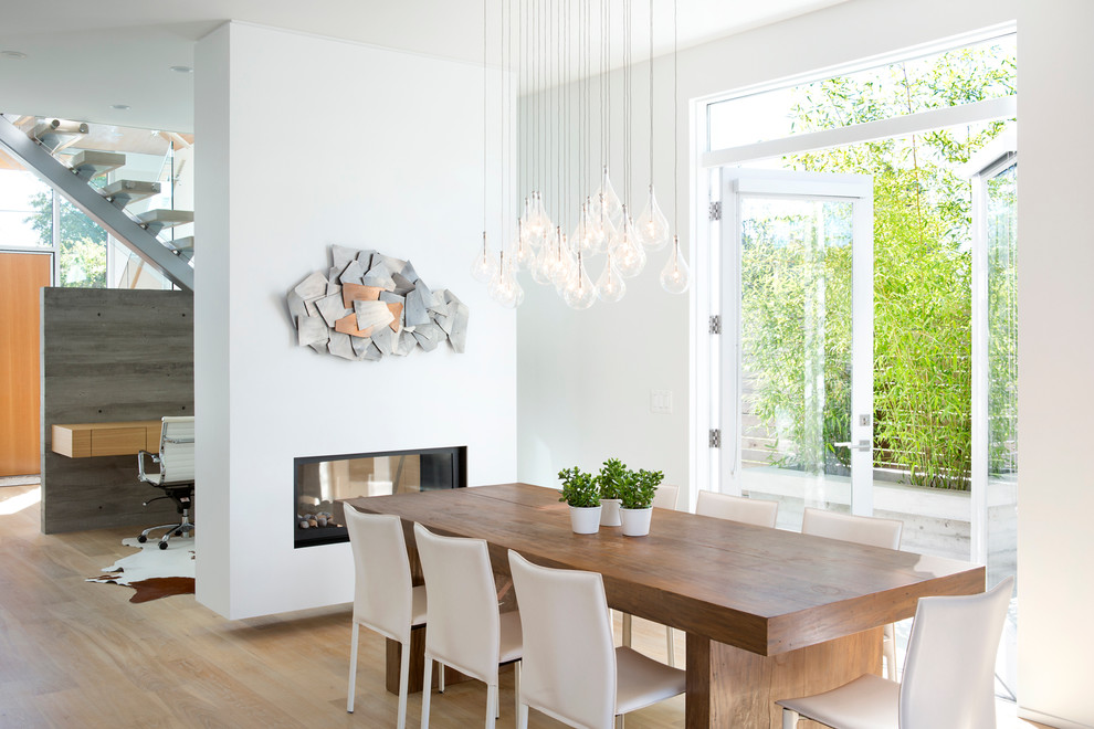 Свежая идея для дизайна: столовая в скандинавском стиле с белыми стенами и двусторонним камином - отличное фото интерьера