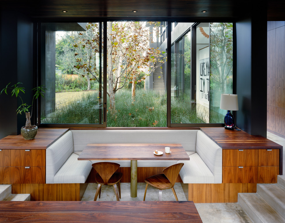 Idée de décoration pour une salle à manger ouverte sur la cuisine minimaliste avec un mur noir, sol en béton ciré, aucune cheminée et éclairage.
