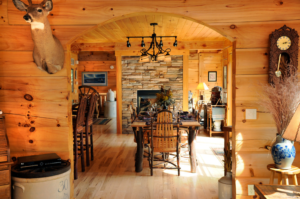 На фото: кухня-столовая среднего размера в стиле рустика с коричневыми стенами, светлым паркетным полом, двусторонним камином и фасадом камина из камня с