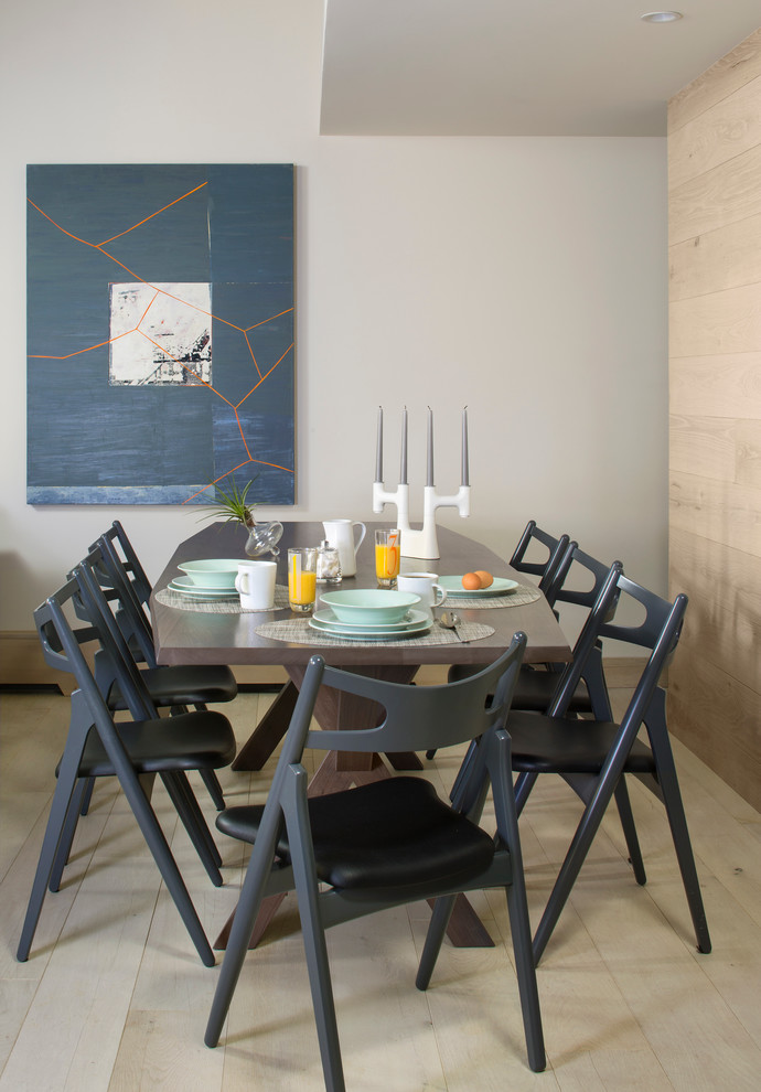 Cette image montre une salle à manger design avec un mur blanc et parquet clair.