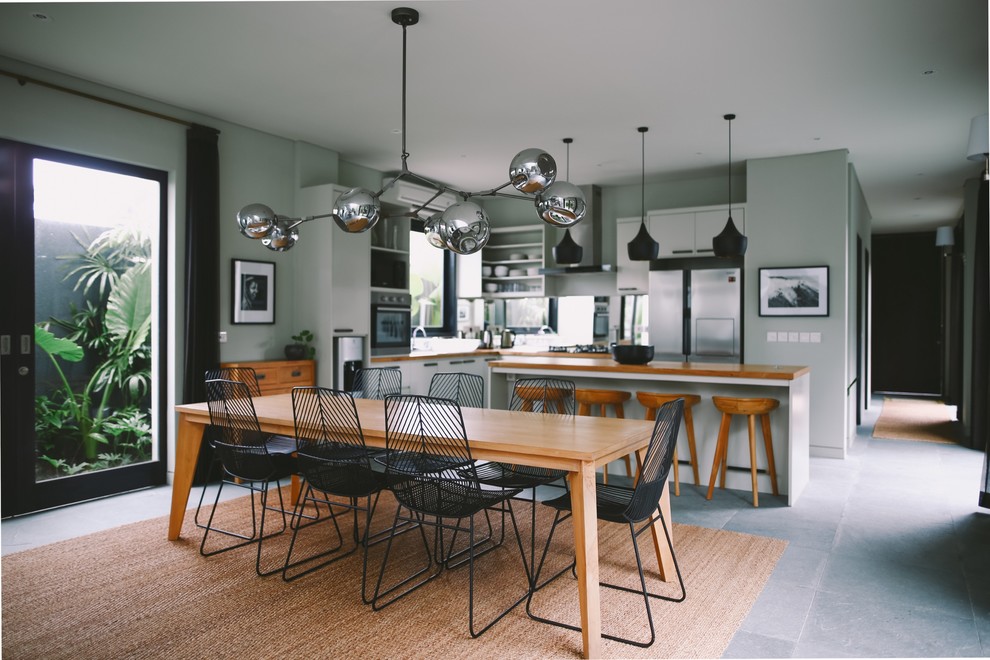 Cette image montre une salle à manger ouverte sur la cuisine design avec un mur gris et un sol gris.