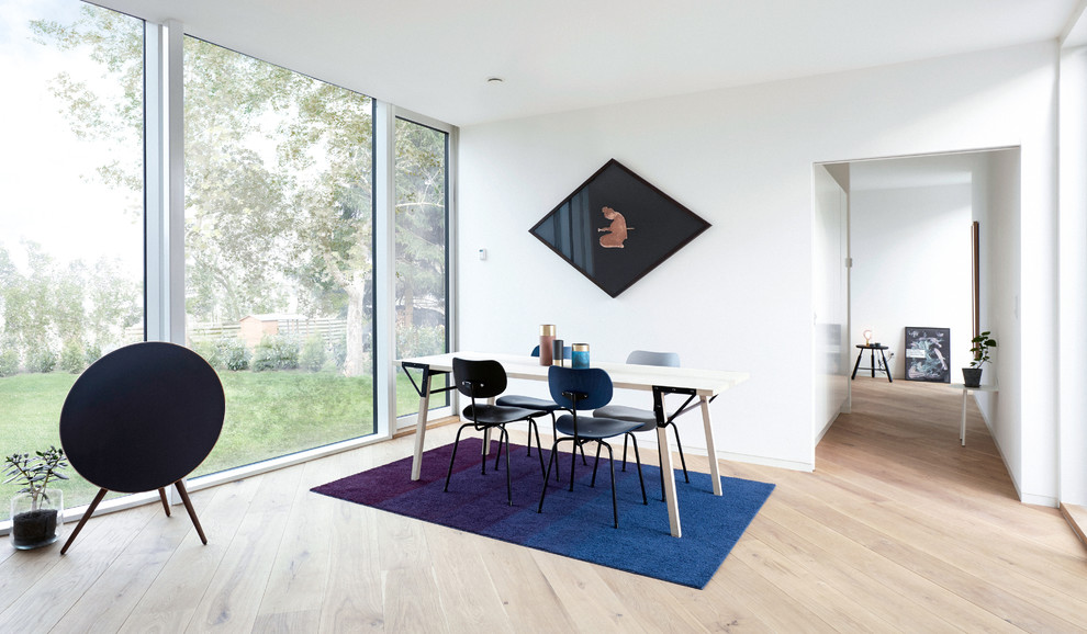 This is an example of a medium sized scandinavian open plan dining room in Copenhagen with white walls and light hardwood flooring.